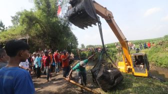 Sejumlah petugas dan warga memindahkan kepala arca Kala saat diangkat dari sungai di Desa Nambaan, Kediri, Jawa Timur, Minggu (12/6/2022). ANTARA FOTO/Prasetia Fauzani
