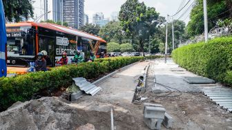 Pekerja menyelesaikan proyek revitalisasi trotoar di Jalan Pattimura, Jakarta Selatan, Senin (13/6/2022). [Suara.com/Alfian Winanto]