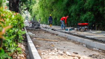 Pekerja menyelesaikan proyek revitalisasi trotoar di Jalan Pattimura, Jakarta Selatan, Senin (13/6/2022). [Suara.com/Alfian Winanto]