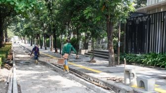 Pekerja menyelesaikan proyek revitalisasi trotoar di Jalan Pattimura, Jakarta Selatan, Senin (13/6/2022). [Suara.com/Alfian Winanto]