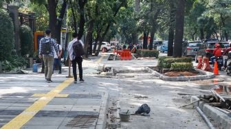 Pekerja menyelesaikan proyek revitalisasi trotoar di Jalan Pattimura, Jakarta Selatan, Senin (13/6/2022). [Suara.com/Alfian Winanto]