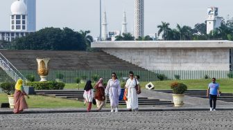 Warga berwisata mengunjungi Monumen Nasional (Monas) di Gambir, Jakarta Pusat, Kamis (16/6/2022). [Suara.com/Alfian Winanto]