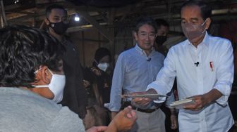 Presiden Joko Widodo (kanan) menyerahkan bantuan langsung tunai (BLT) kepada warga saat mengunjungi Pasar Tradisional di Baros, Serang, Banten, Jumat (17/6/2022). [ANTARA FOTO/Asep Fathulrahman/ foc]
