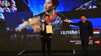 Mantan pebulu tangkis ganda campuran Indonesia Liliyana Natsir (kiri) menunjukkan piagam Hall of Fame dari Federasi Bulu Tangkis Dunia (BWF) yang diserahkan Anggota Dewan BWF Bambang Roedyanto di Istora Senayan, Jakarta, Sabtu (18/6/2022). [ANTARA FOTO/Sigid Kurniawan/YU]
