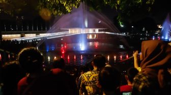 Warga menonton pertunjukan air mancur di Taman Lapangan Banteng, Jakarta Pusat, Sabtu (18/6/2022). [Suara.com/Alfian Winanto]