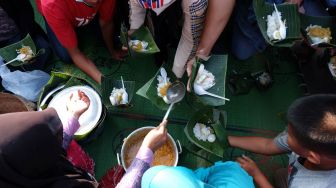Anggota Forum Budaya Mataram membagikan nasi liwet kepada warga saat acara pengukuhan nasi liwet sebagai ikon kuliner Kota Solo di Balai Kota Solo,Jawa Tengah, Minggu (19/6/2022). ANTARA FOTO/Maulana Surya