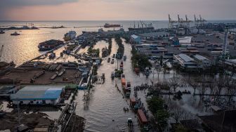 Foto udara ratusan pekerja industri kawasan pelabuhan berjalan menembus banjir limpasan air laut ke daratan atau rob yang merendam kawasan Pelabuhan Tanjung Emas Semarang, Jawa Tengah, Senin (20/6/2022).  ANTARA FOTO/Aji Styawan