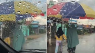 Dua Perempuan Ini Gunakan Payung Jumbo untuk Lindungi Diri dari Hujan, Netizen: Bisa Buat Sekeluarga