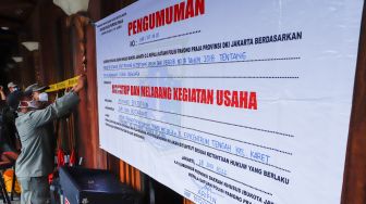 Petugas Satuan Polisi Pamong Praja (Satpol PP) memasang garis polisi saat penutupan dan penyegelan outlet Holywings Epicentrum di Kuningan, Jakarta Selatan, Selasa (28/6/2022). [Suara.com/Alfian Winanto]
