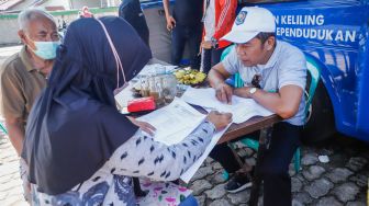 Warga mengunjungi pelayanan keliling Dinas Kependudukan dan Pencatatan Sipil Provinsi DKI Jakarta di halaman Masjid Al Hikmah Hidayah, Cipayung, Jakarta Timur, Rabu (29/6/2022). [Suara.com/Alfian Winanto]