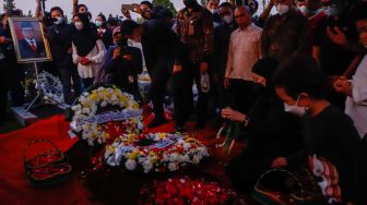 Keluarga menabur bunga di atas pusara Menteri Pendayagunaan Aparatur Negara dan Reformasi Birokrasi (Menpan RB) Tjahjo Kumolo saat prosesi pemakaman di Taman Makam Pahlawan, Kalibata, Jakarta Selatan, Jumat (1/7/2022). [Suara.com/Alfian Winanto]