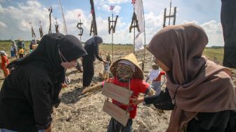 Warga membaca tulisan harapan yang dibuat anak-anak dan dipasang pada orang-orangan sawah berbahan jerami dalam Festival Anak Sawah di kawasan persawahan Kampung Lali Gadget (KLG), Desa Pagerngumbuk, Wonoayu, Sidoarjo, Jawa Timur, Minggu (3/7/2022). [ANTARA FOTO/Umarul Faruq/nym]