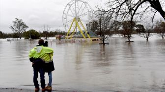 Warga melihat ke taman yang banjir akibat hujan deras di pinggiran Camden, Sydney, Australia, Minggu (3/7/2022). [Muhammad FAROOQ / AFP]
