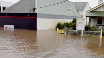 Seorang warga melihat jalanan yang banjir akibat hujan deras di pinggiran Camden, Sydney, Australia, Minggu (3/7/2022). [Muhammad FAROOQ / AFP]
