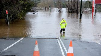 Seorang petugas penyelamat memeriksa area yang terendam banjir akibat hujan deras di pinggiran Camden, Sydney, Australia, Minggu (3/7/2022). [Muhammad FAROOQ / AFP] 
