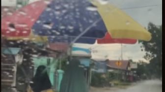 Hujan Deras, Ibu Ini Berjalan Pakai Payung Parasol