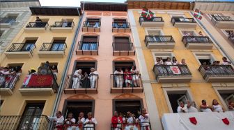 Warga melihat jalanan dari balkon selama acara "encierro" (lari banteng) saat festival San Fermin di Pamplona, Spanyol, Kamis (7/7/2022). [ANDER GILLENEA / AFP]