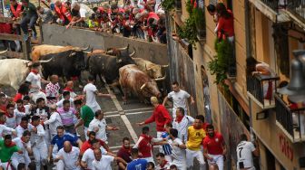 Para peserta berlari di depan banteng selama acara "encierro" (lari banteng) saat festival San Fermin di Pamplona, Spanyol, Kamis (7/7/2022). [MIGUEL RIOPA / AFP]
