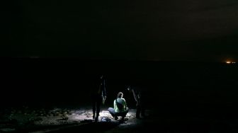 Peneliti melakukan survei pemijahan kepiting tapal kuda di pantai di Area Konservasi Ted Harvey di Dover, Delaware, Amerika Serikat, Jumat (17/6/2022). [Bastien INSAURRALDE / AFP]