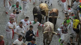 Para peserta berlari di depan banteng selama acara "encierro" (lari banteng) saat festival San Fermin di Pamplona, Spanyol, Kamis (7/7/2022). [MIGUEL RIOPA / AFP]
