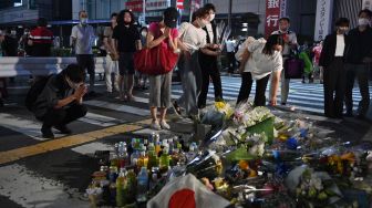 Warga menaruh bunga dan berdoa untuk mantan Perdana Menteri Jepang Abe Shinzo di TKP penembakan di luar Stasiun Yamato Saidaiji di Nara, Jepang, Jumat (8/7/2022). [Philip FONG / AFP]
