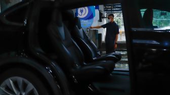 Pengemudi mengisi daya mobil taksi listrik (e-Taxi) di Kantor Pusat Bluebird Group, Mampang Prapatan, Jakarta Selatan, Rabu (13/7/2022). [Suara.com/Alfian Winanto]