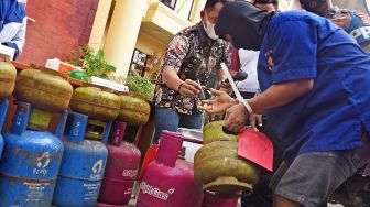 Tersangka penyalahgunaan gas LPG bersubsidi berinisial MU (kanan) memeragakan cara memindahkan isi gas saat ekspos di Mapolda Banten, di Serang, Jumat (15/7/2022). ANTARA FOTO/Asep Fathulrahman
