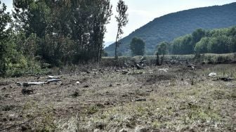 Puing-puing milik pesawat kargo Antonov An-12 yang jatuh terlihat di Desa Palaiochoro, kota Kavala, Yunani, Minggu (17/7/2022). [Sakis MITROLIDIS / AFP]