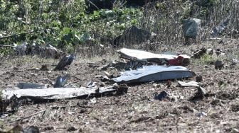 Puing-puing milik pesawat kargo Antonov An-12 yang jatuh terlihat di Desa Palaiochoro, kota Kavala, Yunani, Minggu (17/7/2022). [Sakis MITROLIDIS / AFP]