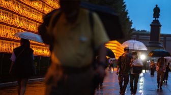 Orang-orang berjalan di antara lentera yang menyala saat festival Mitama Matsuri di Kuil Yasukuni, Tokyo, Jepang, Kamis (14/7/2022). [Philip FONG / AFP]