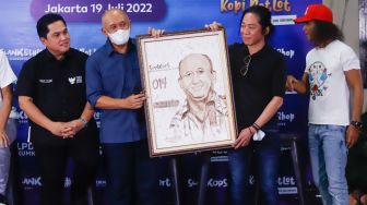 Personil grup band Slank Abdee Negara memberi cinderamata kepada Menteri Koperasi dan UKM Teten Masduki saat launching koperasi Slankops di Jalan Potlot, Jakarta Selatan, Selasa (19/7/2022). [Suara.com/Alfian Winanto]