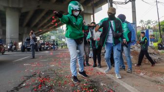 Warga sekitar saat menggelar aksi tabur bunga di Jalan Transyogi Cibubur, Bekasi, Jawa Barat, Rabu (20/7/2022). [Suara.com/Alfian Winanto]