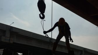 Petugas Dinas Perhubungan (Dishub) DKI Jakarta menurunkan beton pembatas jalan untuk menutup Jembatan Kapin di Duren Sawit, Jakarta Timur, Kamis (28/7/2022). [Suara.com/Alfian Winanto]