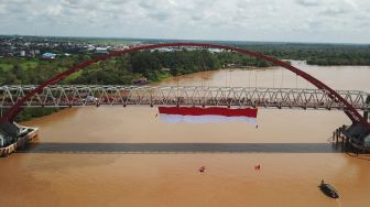 Foto udara sebuah bendera merah putih dibentangkan di Jembatan Kahayan, Palangka Raya, Kalimantan Tengah, Sabtu (6/8/2022). ANTARA FOTO/Makna Zaezar