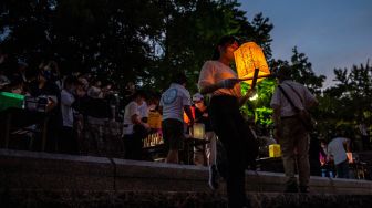 Warga melepas lentera kertas di Sungai Motoyasu untuk memperingati 77 tahun serangan bom atom di samping kubah bom atom, Hiroshima, Jepang, Sabtu (6/8/2022). [Philip FONG / AFP]