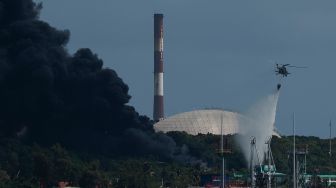 Helikopter pemadam kebakaran menjatuhkan air ke tangki minyak yang terbakar di Matanzas, Kuba, Sabtu (6/8/2022). [Yamil LAGE / AFP]
