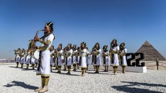 Anggota marching band yang mengenakan pakaian Mesir kuno tampil dsaat acara Pyramids Air Show 2022 di dataran tinggi Piramida Giza, Mesir, Rabu (3/8/2022). [Mahmoud Khaled / AFP]
