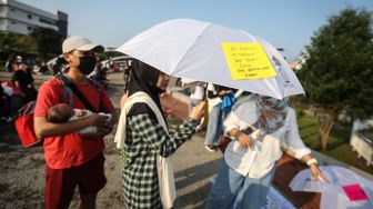 Seorang peserta membawa payung yang berisi pesan pentingnya menyusui di Alun-Alun Kota Depok, Depok, Jawa Barat, Minggu (7/8/2022). [ANTARA FOTO/Asprilla Dwi Adha/nym]
