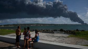 Warga melihat asap hitam akibat kebakaran tangki minyak di Matanzas, Kuba, Sabtu (6/8/2022). [Yamil LAGE / AFP]
