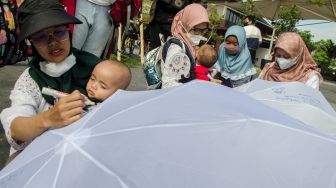 Peserta dari Asosiasi Ibu Menyusui Indonesia (AIMI) Jabar menulis aspirasi pada payung putih saat Aksi Payung AspirASI di Bandung, Jawa Barat, Minggu (7/8/2022). [ANTARA FOTO/Novrian Arbi/nym]