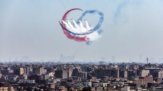 Pesawat K-8E Karakorum dari tim aerobatik Angkatan Udara Mesir 'Silver Stars' bermanuver saat acara Pyramids Air Show 2022 di dataran tinggi Piramida Giza, Mesir, Rabu (3/8/2022). [Mahmoud Khaled / AFP]