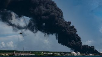 Helikopter pemadam kebakaran menjatuhkan air ke tangki minyak yang terbakar di Matanzas, Kuba, Sabtu (6/8/2022). [Yamil LAGE / AFP]
