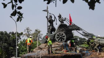 Pekerja membersihkan patung Arjuna Wijaya atau yang lebih dikenal sebagai patung kuda di jalan Medan Merdeka Barat, Jakarta Barat, Selasa (9/8/2022). [Suara.com/Alfian Winanto]