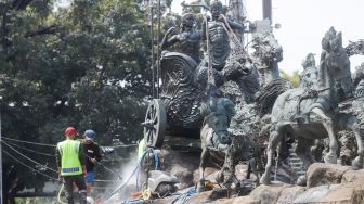 Pekerja membersihkan patung Arjuna Wijaya atau yang lebih dikenal sebagai patung kuda di jalan Medan Merdeka Barat, Jakarta Barat, Selasa (9/8/2022). [Suara.com/Alfian Winanto]