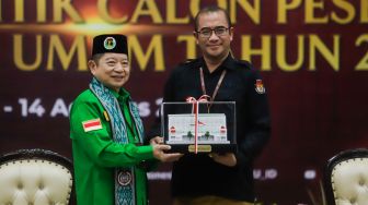 Ketua Komisi Pemilihan Umum (KPU) Hasyim Asy'ari (kanan) memberikan cinderamata kepada Ketua Umum Partai Persatuan Pembangunan (PPP)  Suharso Monoarfa saat Pendaftaran Partai Politik Calon Peserta Pemilu tahun 2024 di Kantor KPU, Jakarta Pusat, Rabu (10/8/2022). [Suara.com/Alfian Winanto]