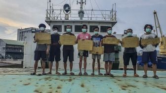 Delapan ABK asal Indonesia yang terkatung-katung memegang poster berisi permintaan untuk pulang di atas kapal kargo MV Jian Ye yang diduga milik perusahaan asal Hong Kong di Pelabuhan Kaohsiung, Taiwan, Kamis (11/8/2022).  ANTARA FOTO/Fahmi Fahmal Sukardi
