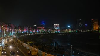 Bangunan di pinggir laut Marine Drive terlihat menyala dengan warna bendera nasional India di Mumbai, India, Sabtu (13/8/2022). [Punit PARANJPE / AFP]