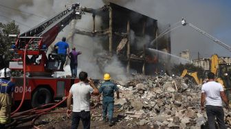 Petugas pemadam berusaha memadamkan gudang kembang api yang terbakar di Pasar Surmalu, Yerevan, Armenia, Minggu (14/8/2022). [Karen MINASYAN / AFP]