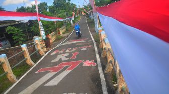 Warga melintas disamping bendera merah putih terpanjang di Desa Honggosoco, Jekulo, Kudus, Jawa Tengah, Selasa (16/8/2022). ANTARA FOTO/Yusuf Nugroho
