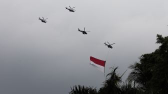 Helikopter gabungan milik TNI-Polri terbang melintas dengan bendera merah putih raksasa di atas Monas saat Peringatan Detik-Detik Proklamasi di Perpustakaan Nasional, Jakarta Pusat, Rabu (17/8/2022). [Suara.com/Alfian Winanto]